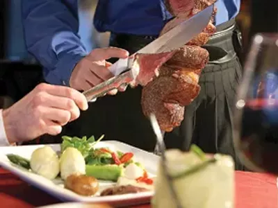 A server cuts picanha (sa Brazilian rump roast) at Gaucho Brazilian Steakhouse.