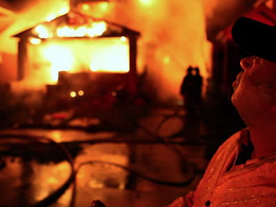 Detroit Fire Department's FEO Dave Parnell stands outside a burning home.