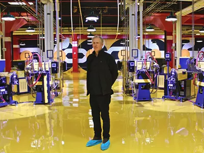 Robert Sestok in Third Man Records' new vinyl factory, with his mural behind him.