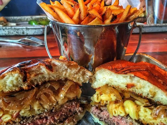The Rusted Crow's mac and cheese burger with grilled onions, bacon, and a mac and cheese patty between the buns.