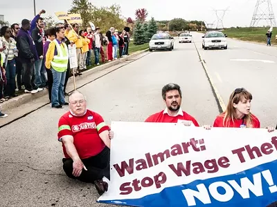 Wage theft protesters stage a sit-down protest to block the entrance of the Walmart distribution center in Elwood, Ill.