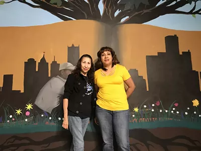 Cleaning in Action founders Carolina Torres and Maria Perez in front of a mural inside Grace in Action.
