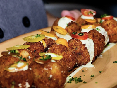 Arancini with kale, prosciutto di parma, fresh mozzarella, truffle, and arugula cream.