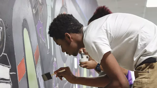 A student at Detroit's Southeastern High School, where there is no formal art program, paints a mural as part of a new partnership between the school and the Heidelberg Project.