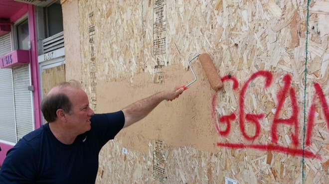 Detroit Mayor Mike Duggan buffs graffiti bearing his name in 2013.