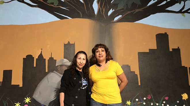 Cleaning in Action founders Carolina Torres and Maria Perez in front of a mural inside Grace in Action.