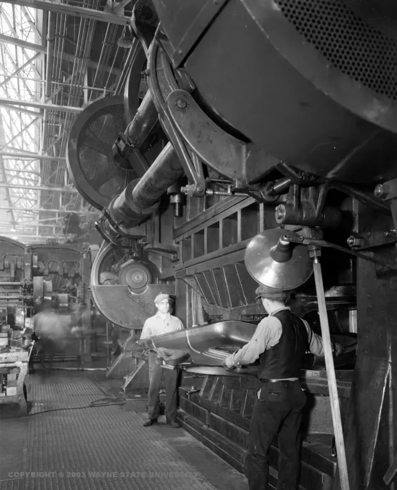 1932 - Ford Motor Company in River Rouge Factory workers taking out what appears to be a car door from a big metal press.