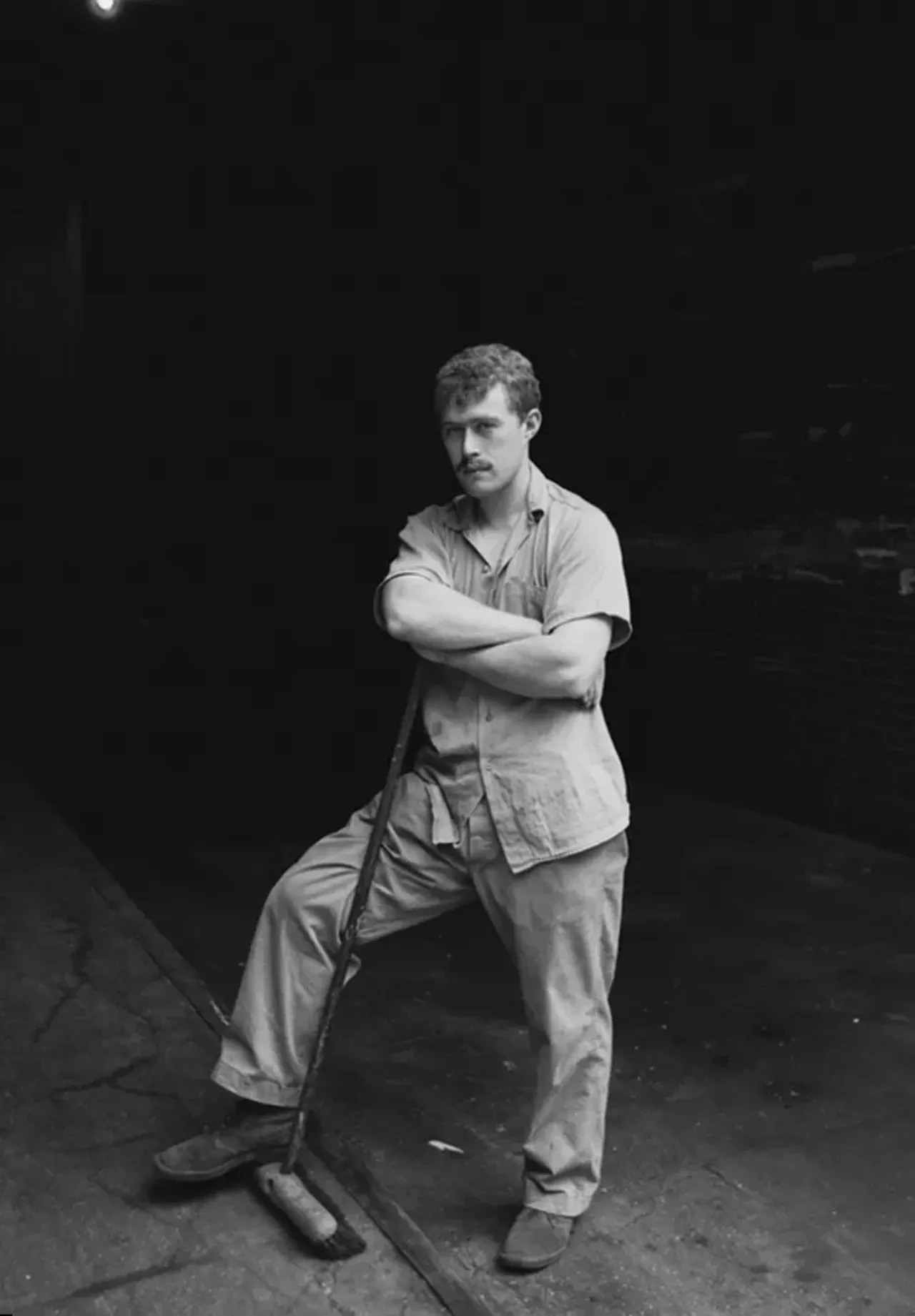 Sweeper in alley behind J.L. Hudson - "I was walking down an alley around J.L. Hudson building when I saw this guy sweeping. He was the only person around. He stopped and looked up when he saw me and I took his photo. I think the lightbulb makes the shot." &#124; Photos: Bill Rauhauser