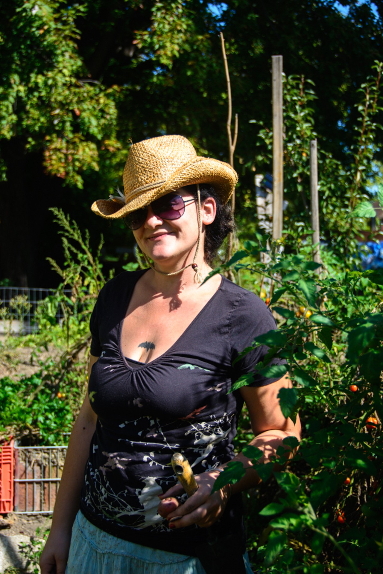 0: Sara Swor,Detroit, Michigan, proudly stands next to a towering tomato plant. She has been working the garden for two years now, and most of her meals come from the garden.
