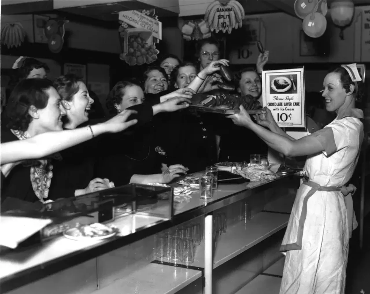 1930s | Uniformed waitress offers tray of food to striking workers at lunch counter at Woolworth department store in Detroit, Michigan, during sit-down strike.