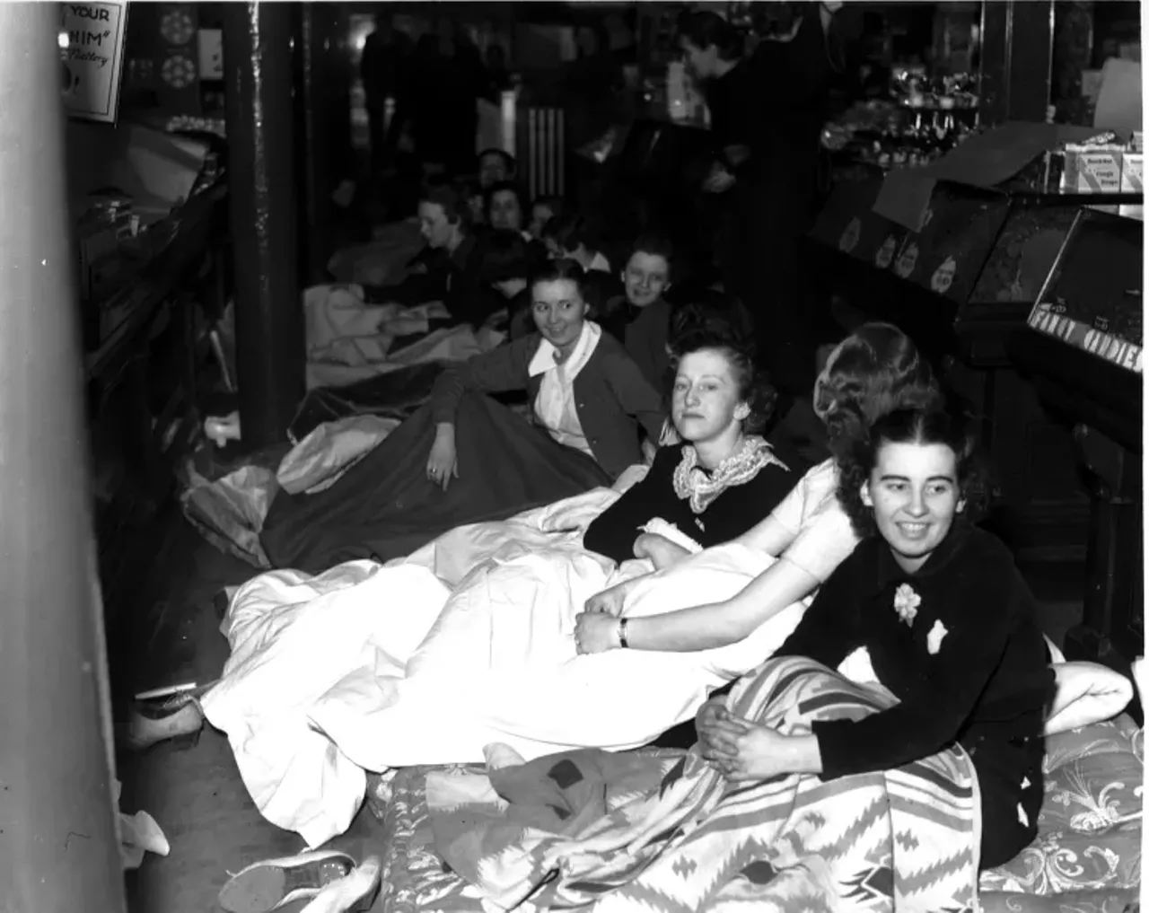 1930s | Striking employees sit on floor under blankets during sit-down strike at Woolworth department store in Detroit, Michigan.