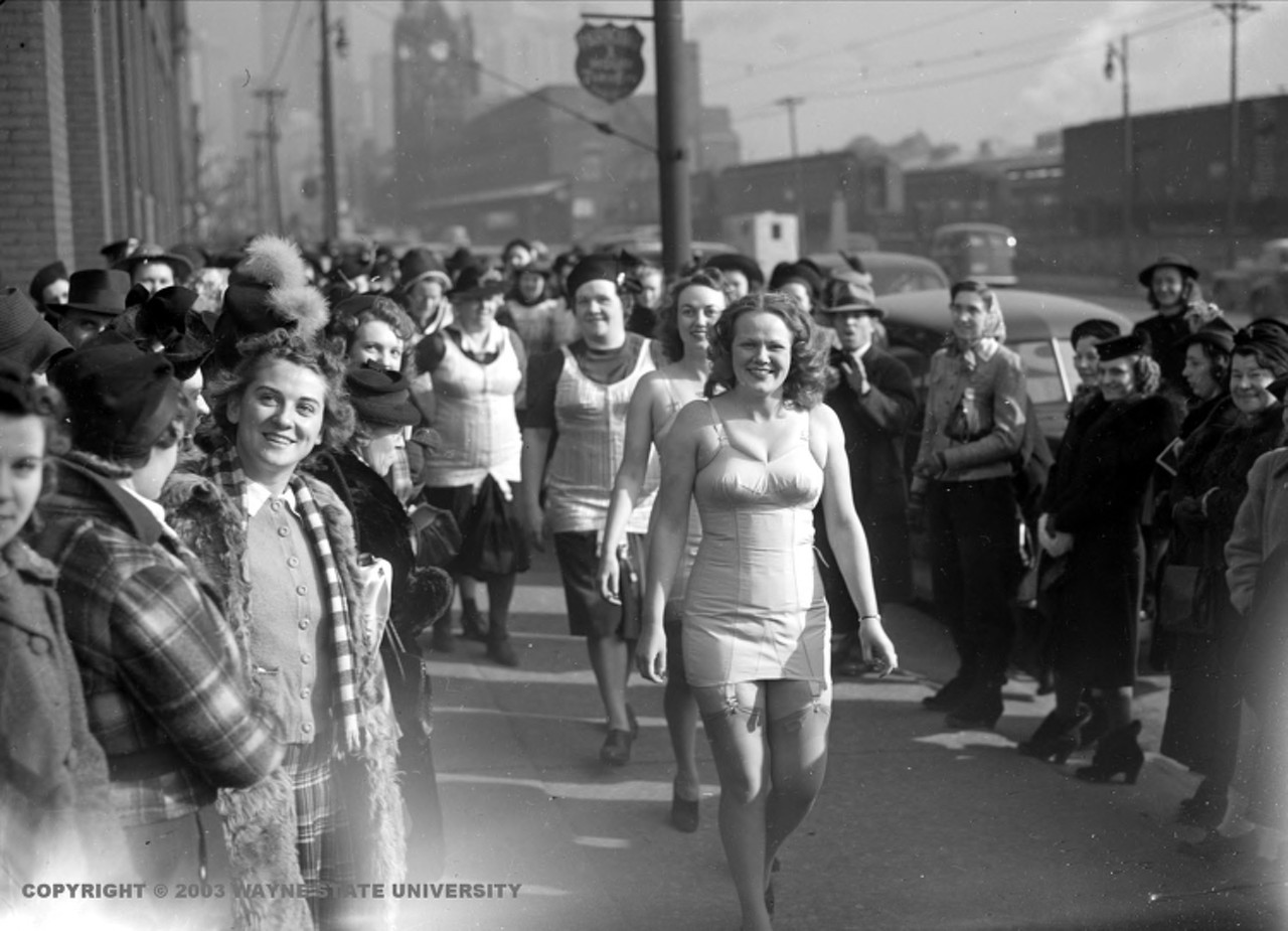 1940s | Two women wearing only corsets, stocking and heels lead group of striking workers of the American Lady Corset Company in Detroit, Michigan.