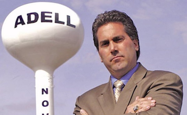 Kevin Adell posing next to a water tower bearing his name at the site of the contested property in Novi.