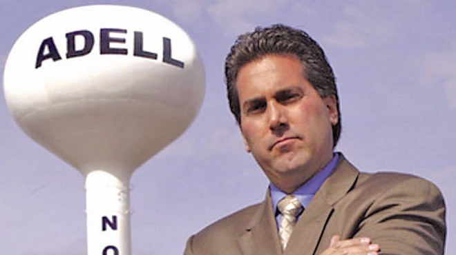 Kevin Adell posing next to a water tower bearing his name at the site of the contested property in Novi.