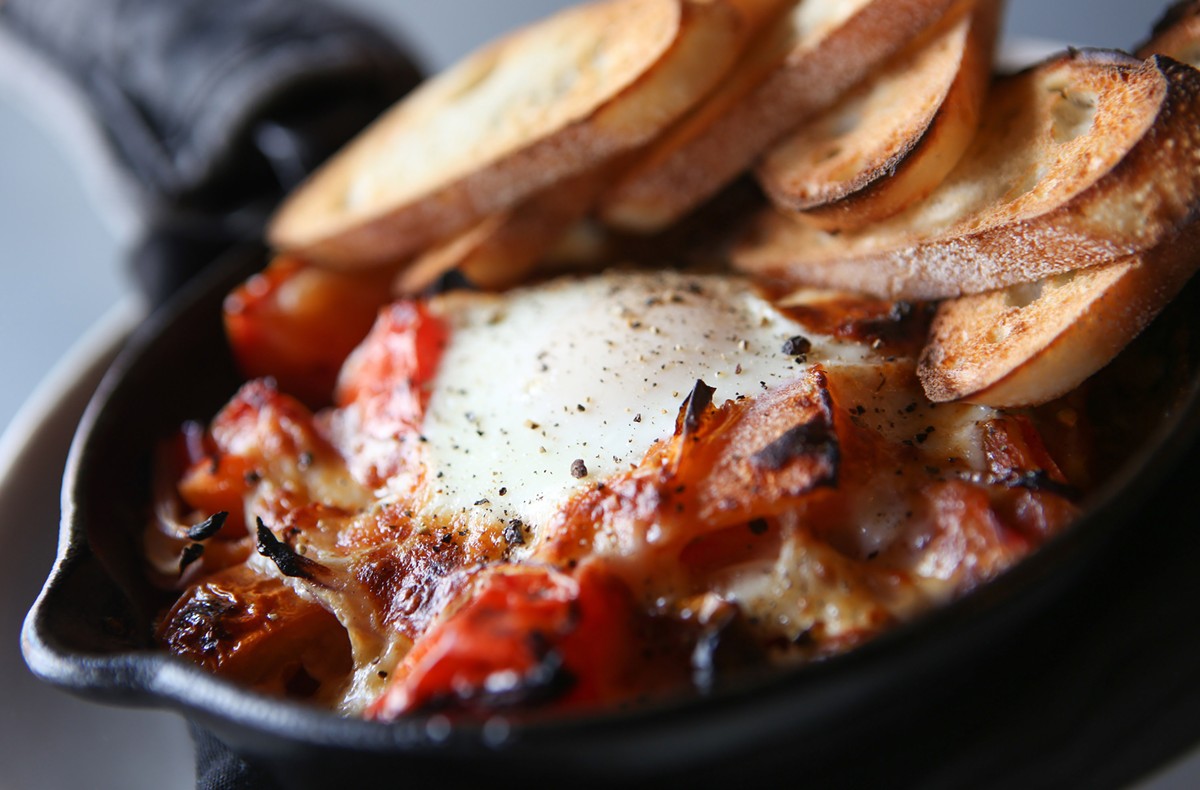 Tomatoes in Cast Iron, heirloom tomatoes, sofrito, egg, cheese curd, and baguette, from Lucy & the Wolf in Northville.
