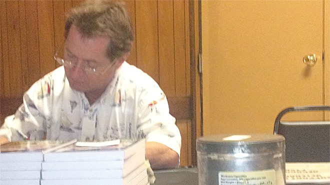 Irvin Rosenfeld signs copies of his book with one of his U.S. cannabis supply cans nearby.