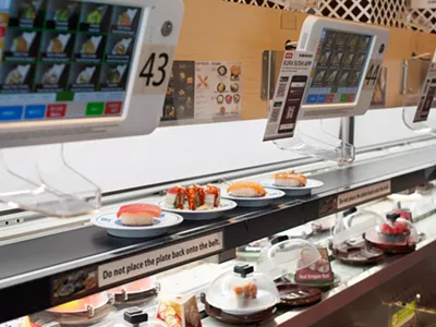 A conveyor belt delivers plates of sushi to customers.