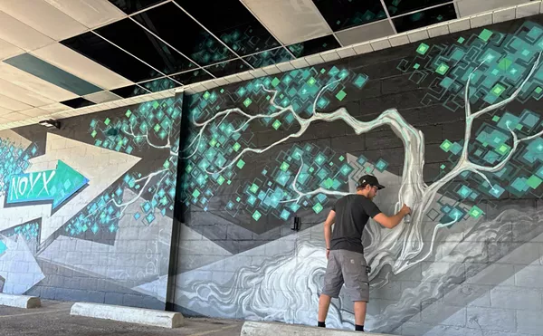 Detroit artist Jonathan Sandberg, also known as Seymor, paints a mural on the side of Noxx Cannabis in Pleasant Ridge.