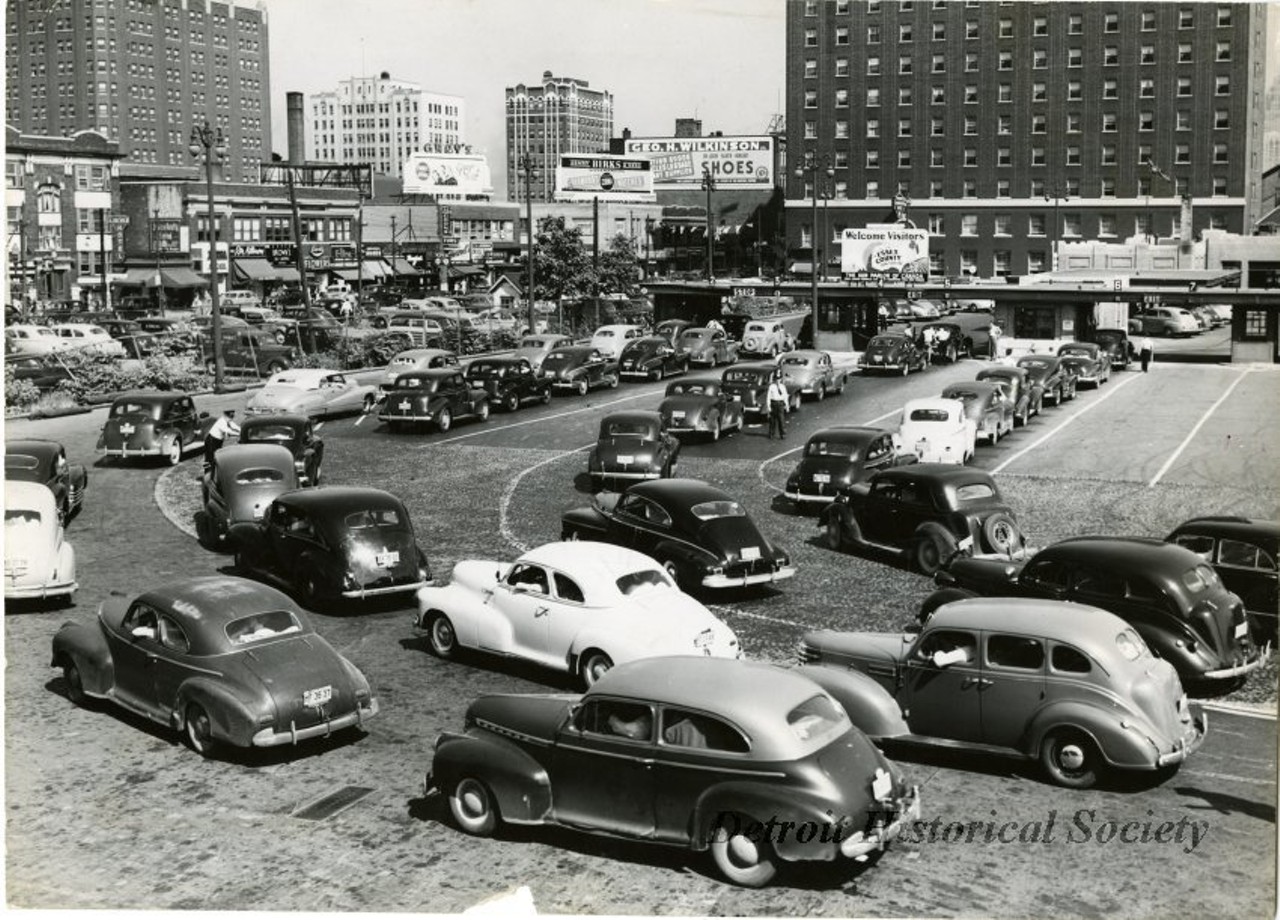 "Black and white photo of the busy lanes of traffic approaching the inspection booths beyond the Windsor exit of the Detroit-Windsor Tunnel during the Fourth of July holiday, 1947. "Jul 4 1947" is stamped on the verso below a clipping from the Windsor Daily Star:
Hard-working customs and immigration men started to "celebrate" the Fourth of July at the Detroit-Windsor Tunnel last nigh when the first influx of American holidaymakers hit this port of entry. Officials predicted records would be shattered before the flow of tourists ends tonight. The picture above shows part of the mass "invasion" of American cars waiting to be cleared through the tunnel facilities into downtown Windsor. Although the bulk of the cars were from Detroit and other nearby points in Michigan, any autos from other states were counted in the early lineups. (Star Staff Photo)"