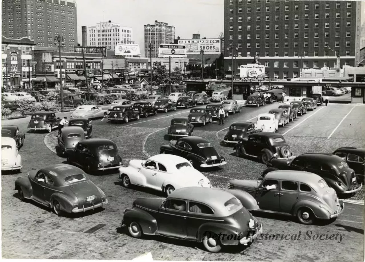 "Black and white photo of the busy lanes of traffic approaching the inspection booths beyond the Windsor exit of the Detroit-Windsor Tunnel during the Fourth of July holiday, 1947. "Jul 4 1947" is stamped on the verso below a clipping from the Windsor Daily Star: Hard-working customs and immigration men started to "celebrate" the Fourth of July at the Detroit-Windsor Tunnel last nigh when the first influx of American holidaymakers hit this port of entry. Officials predicted records would be shattered before the flow of tourists ends tonight. The picture above shows part of the mass "invasion" of American cars waiting to be cleared through the tunnel facilities into downtown Windsor. Although the bulk of the cars were from Detroit and other nearby points in Michigan, any autos from other states were counted in the early lineups. (Star Staff Photo)"