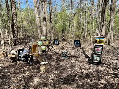 With a similar embrace of the natural surroundings, artist James Rodriguez sat painting a landscape, surrounded by his other paintings of the natural world hanging from trees nearby with a Henry David Thoreau-type vibe.