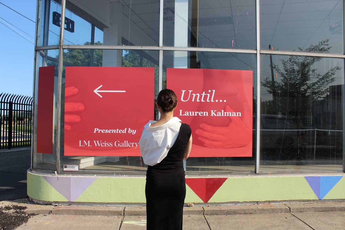 I.M. Weiss Gallery director Isabelle Weiss stands in front of a wayfinding sign for her latest exhibition in Stanton Yards.