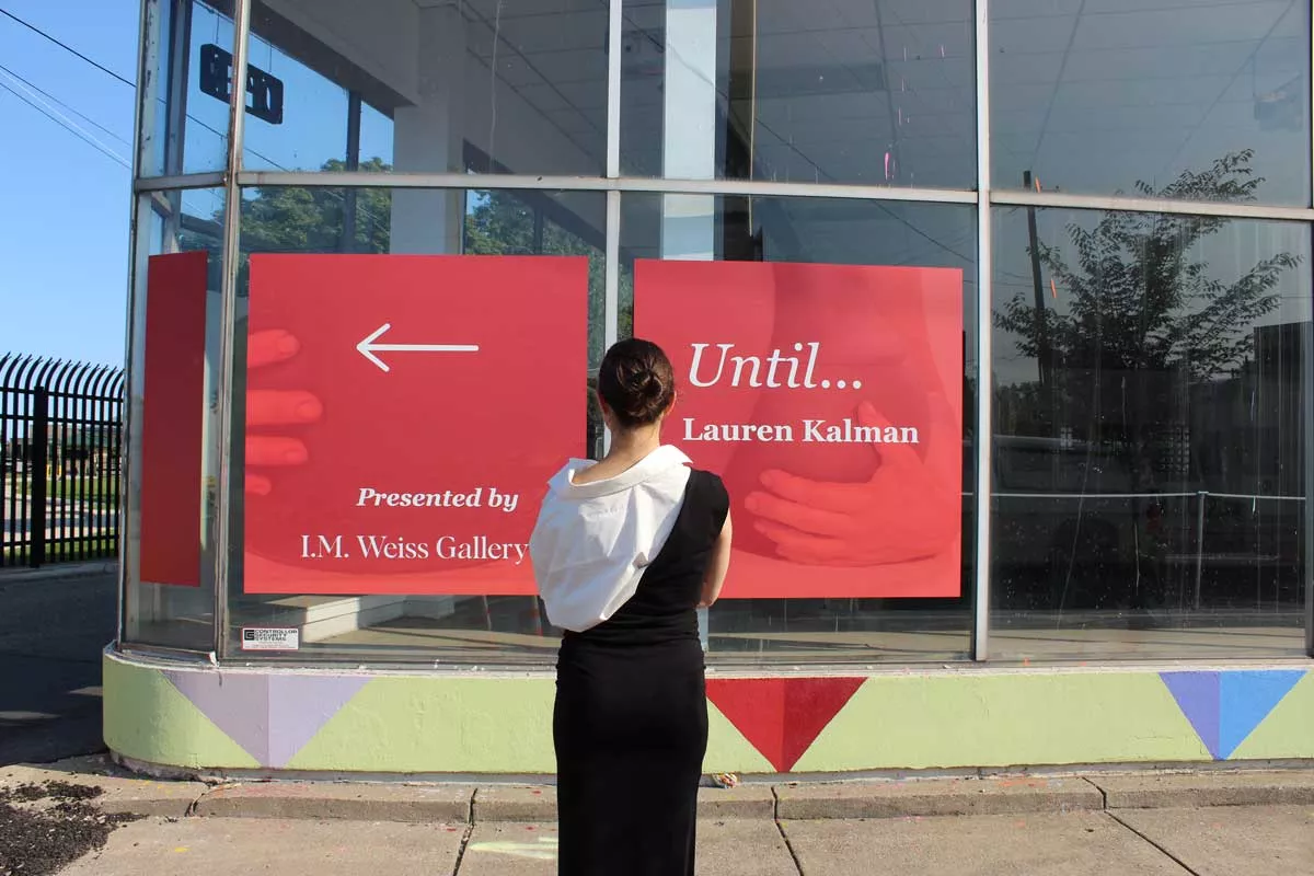 Image: I.M. Weiss Gallery director Isabelle Weiss stands in front of a wayfinding sign for her latest exhibition in Stanton Yards.