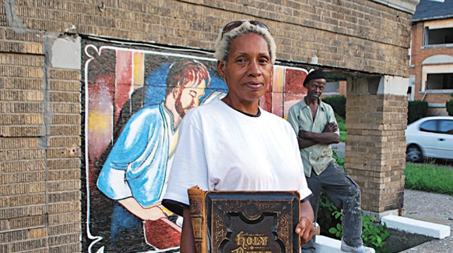 Kathina Carey, with sign painter Leon Goodin in the background, stands by the apartment building that she made into her canvas.