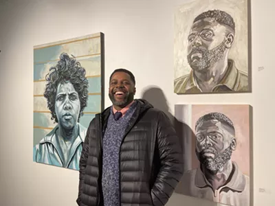 Artist Senghor Reid next to his paintings at the Revelations exhibit.