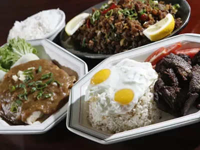 Lumpia sariwa (fresh vegetable eggroll topped with peanut garlic sauce), left, sisig (crispy pork with ginger sauce on sizzling hot plate), upper right, and tap-silog (marinated sirloin with garlic fried rice topped with fried eggs), front, from New Lutong Pinoy in Madison Heights