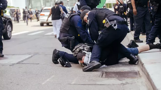 Police detain an antiwar protester in Detroit on Sunday.