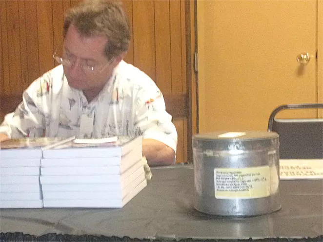 Irvin Rosenfeld signs copies of his book with one of his U.S. cannabis supply cans nearby.