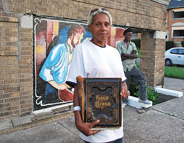 Kathina Carey, with sign painter Leon Goodin in the background, stands by the apartment building that she made into her canvas.