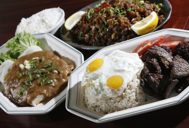 Lumpia sariwa (fresh vegetable eggroll topped with peanut garlic sauce), left, sisig (crispy pork with ginger sauce on sizzling hot plate), upper right, and tap-silog (marinated sirloin with garlic fried rice topped with fried eggs), front, from New Lutong Pinoy in Madison Heights