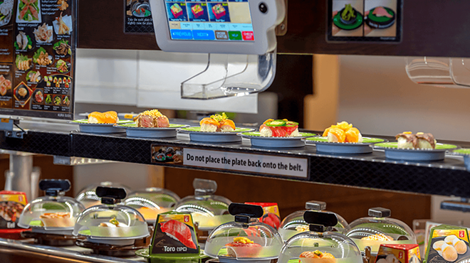 A conveyor belt delivers plates of sushi to customers.