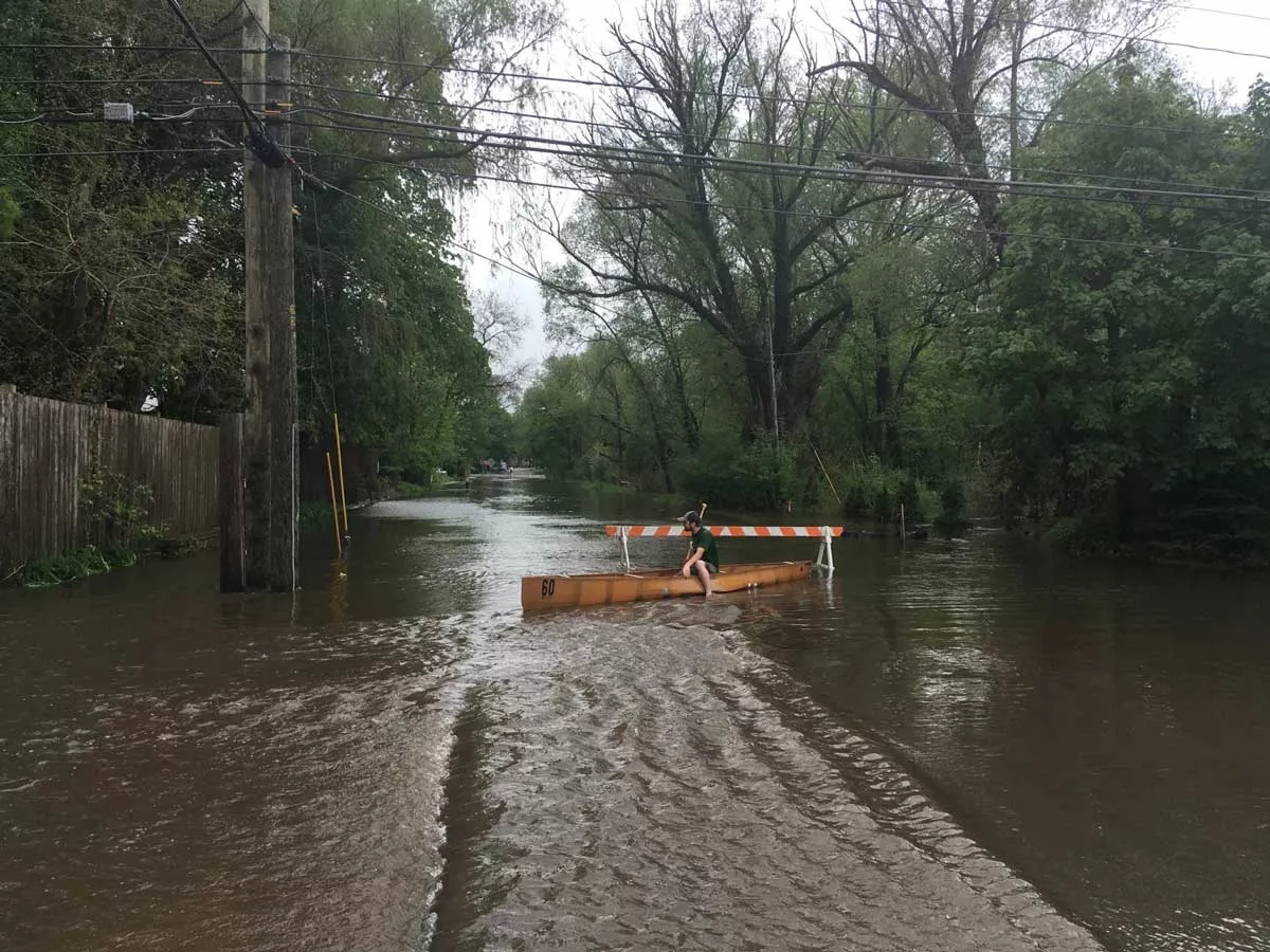 Image: A person sits in a canoe on a Traverse City road after heavy rains flooded the area in May 2020.