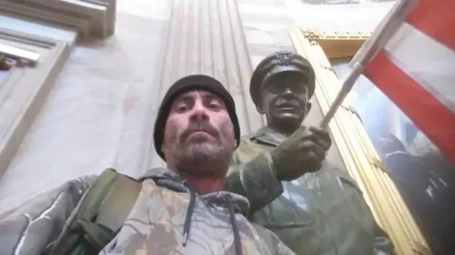 Anthony Robert Williams poses next to statue in U.S. Capitol.