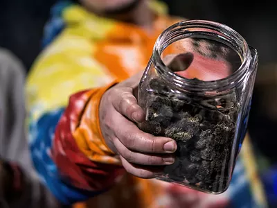 A man holding a jar of cannabis flower.