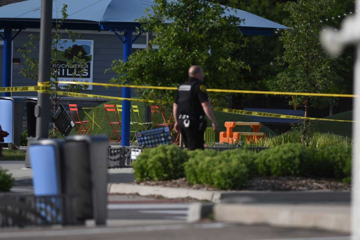 A police officer walks across the plaza of the Brooklands Plaza Splash Pad in Rochester Hills, Mich., where police say there was an active shooter Saturday, June 15, 2024.