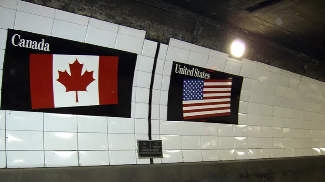 Flags of Canada and the United States over a metal boundary marker in the Detroit-Windsor Tunnel.