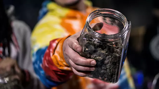 A man holding a jar of cannabis flower.