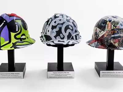 The hardhats painted by Phillip Simpson, Eric “El Cappy” Lowry, and Mike Han will benefit Downtown Boxing Gym, The Konnection, and Junior Achievement of Southeastern Michigan.