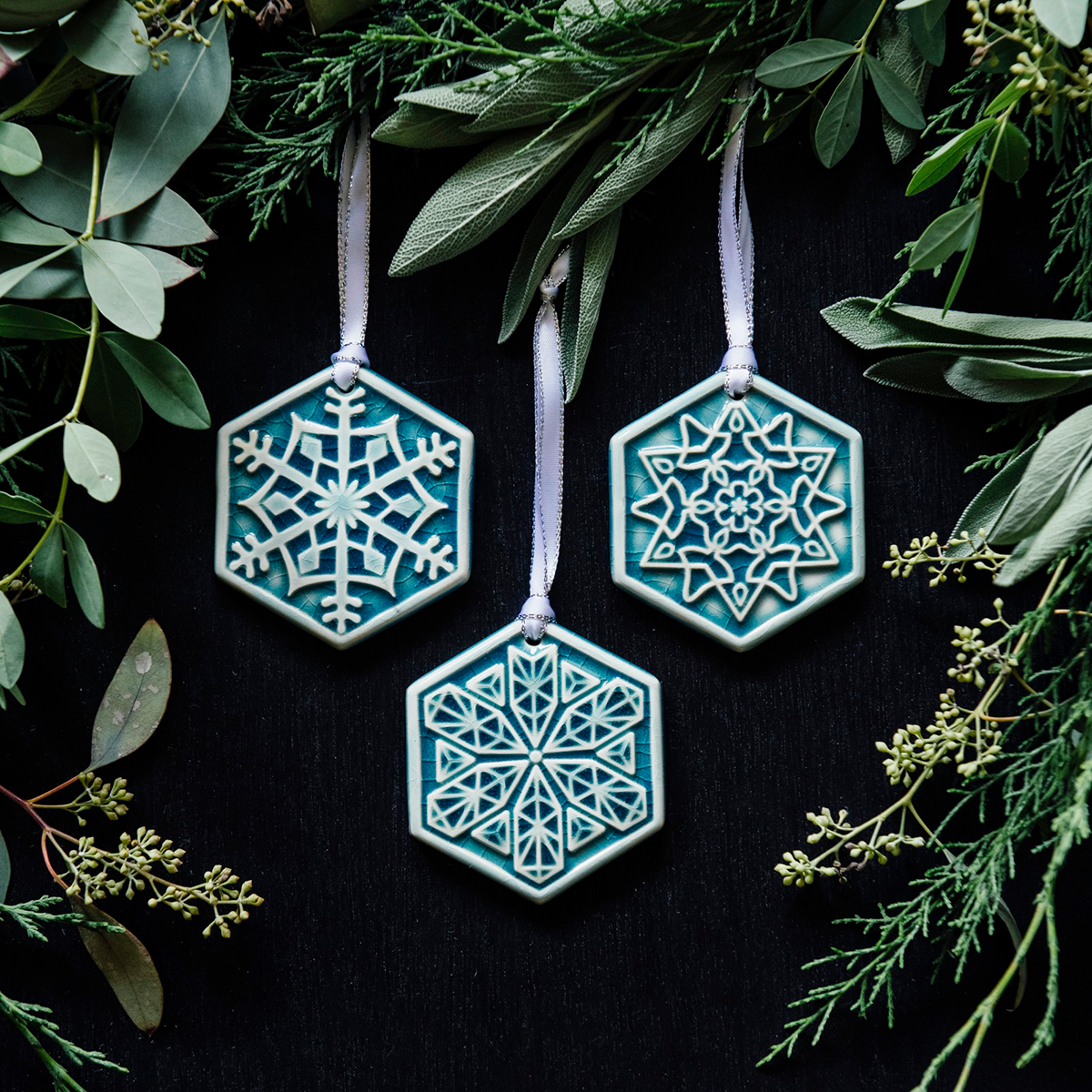 A set for three ceramic snowflake ornaments in a pale blue color. Each snowflake has a unique design.