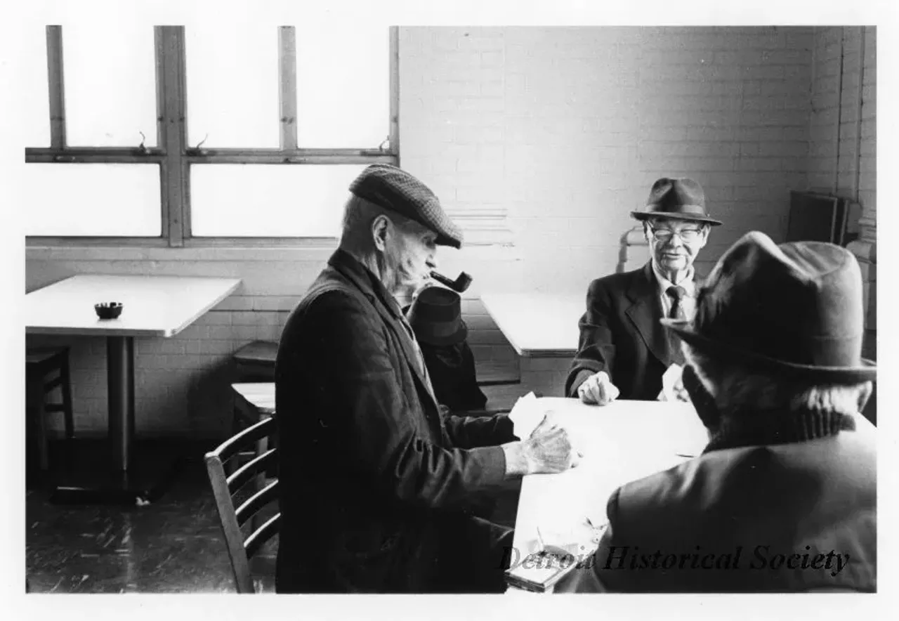 "Black and white photographic print depicting three older men playing cards at a table in the Belle Isle Casino. Dated November 1973."