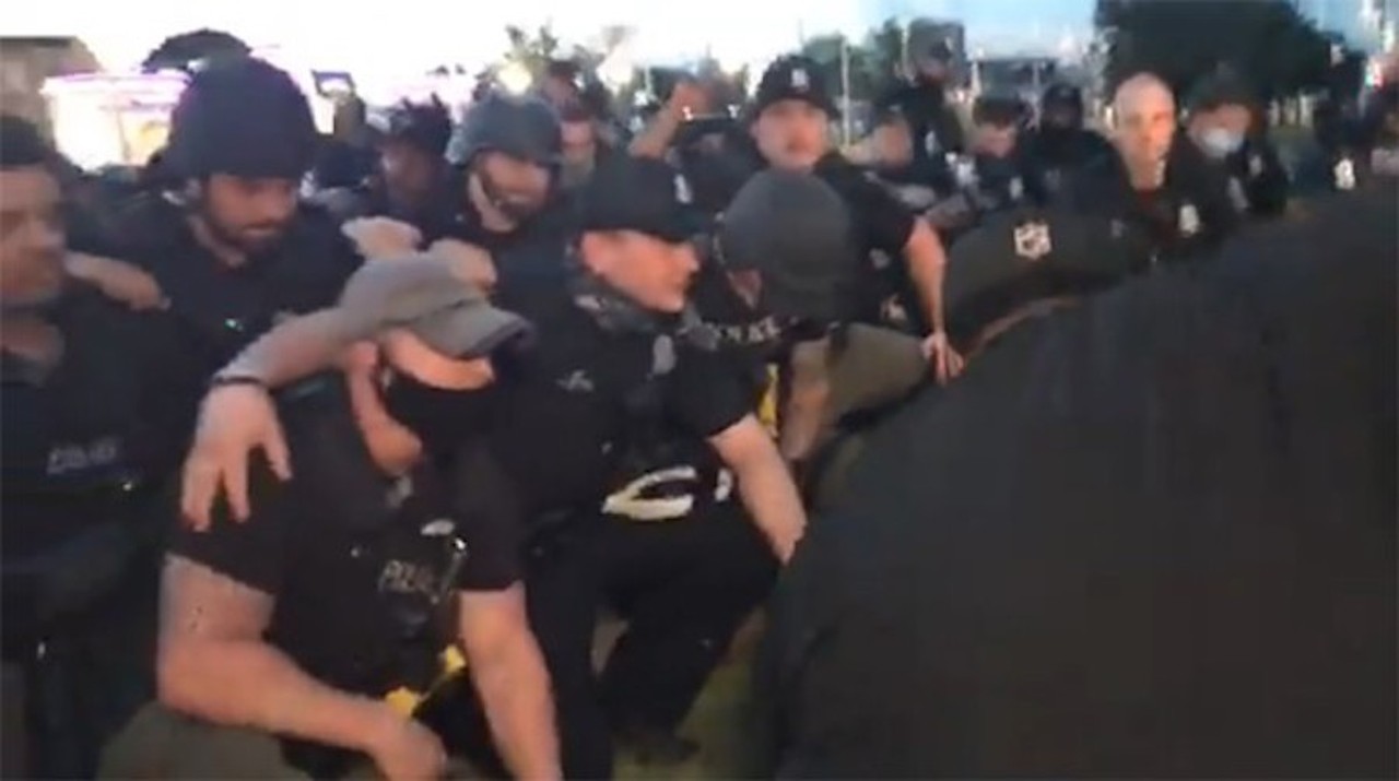 June
If Kneel Street could talk: Oh, boy, was this year filled with virtue signaling and performative hypocrisy! And no one pulled off 2020&#146;s hottest trends quite like the Detroit Police Department, who kneeled for the cameras minutes after arresting about 100 peaceful Black Lives Matter protesters. Kneeling, of course, became a statement for the Black Lives Matter movement when San Francisco 49ers quarterback Colin Kaepernick took a knee during the national anthem of a 49ers game in protest of police brutality in 2016. The symbolic gesture was bastardized when a Minneapolis police officer kneeled on the neck of George Floyd, an unarmed Black man who was killed as a result of not being able to breathe due to, you know, murderous and racist police. Anyway, during what would become a violent year between DPD and Black Lives Matter protesters &#151; specifically, the advocacy group Detroit Will Breathe &#151; not only did they use excessive force when dealing with protesters, like tear gas, chokeholds, and rubber bullets, but they had the audacity to kneel for the cause &#133; for cameras &#133; literally minutes after aggressively slapping zip-ties on nearly 100 protesters, none of whom had attacked police, destroyed public or private property, nor were they looting or starting fires. 
Photo via Screengrab/Facebook