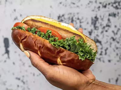 “The 313” is a Beyond sausage topped with kale, tomato, vegan mayo, and mustard on a pretzel bun.