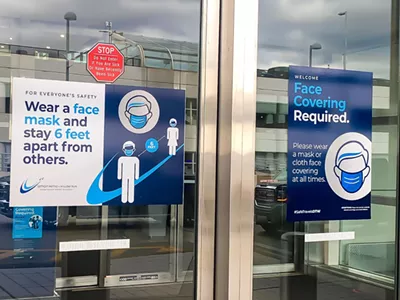 Entrance door of DTW terminal building with sign requiring masks.