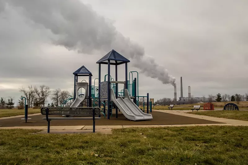 Playground in William C. Sterling State Park with billowing smokestack in the background. - Shutterstock