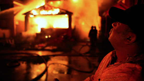 Detroit Fire Department's FEO Dave Parnell stands outside a burning home. - BURN FILM