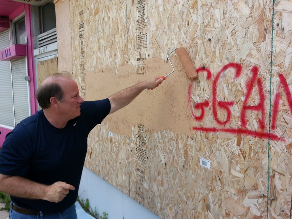 Detroit Mayor Mike Duggan buffs graffiti bearing his name in 2013. - JON HEWETT/WWJ